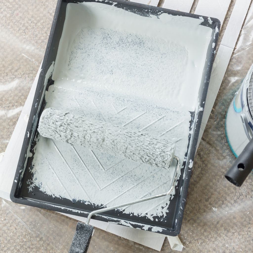 Aerial view of a paint tray with dried paint and a paint roller sitting in the tray.
